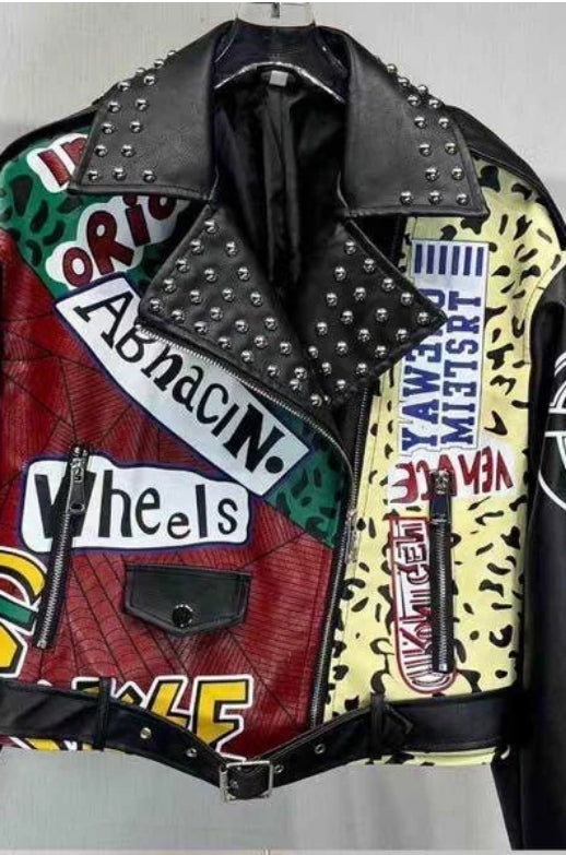 Gros plan d’une veste biker en simili cuir avec patchs graphiques, clous et coupe oversize.